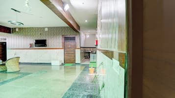 Un vestíbulo de hotel con una recepción, un área de estar y una cocina al fondo.
