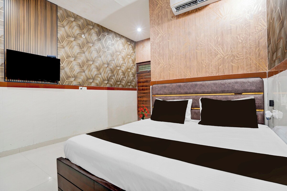 A hotel room with a bed, a television mounted on the wall, and a patterned wall design.