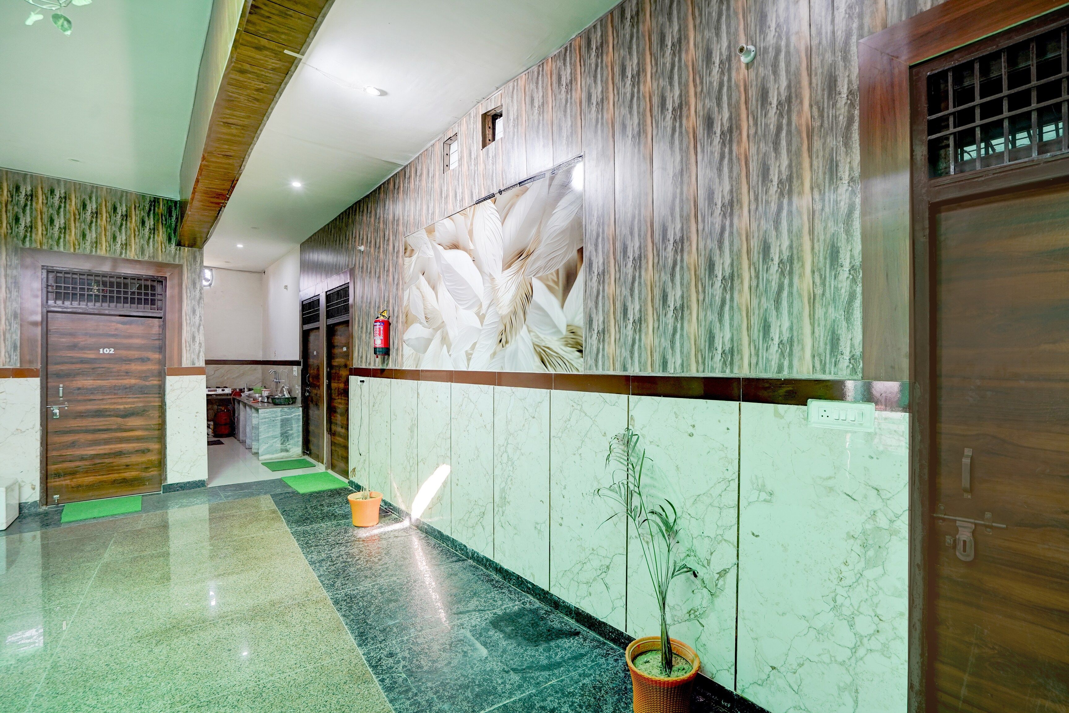 Una zona de recepción con pared de mármol, puerta de madera y un felpudo verde en el suelo.