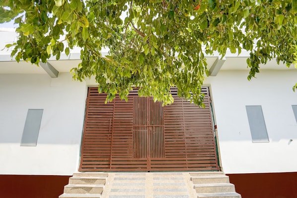 A building entrance with a set of stone steps leading up to a door with horizontal slats.