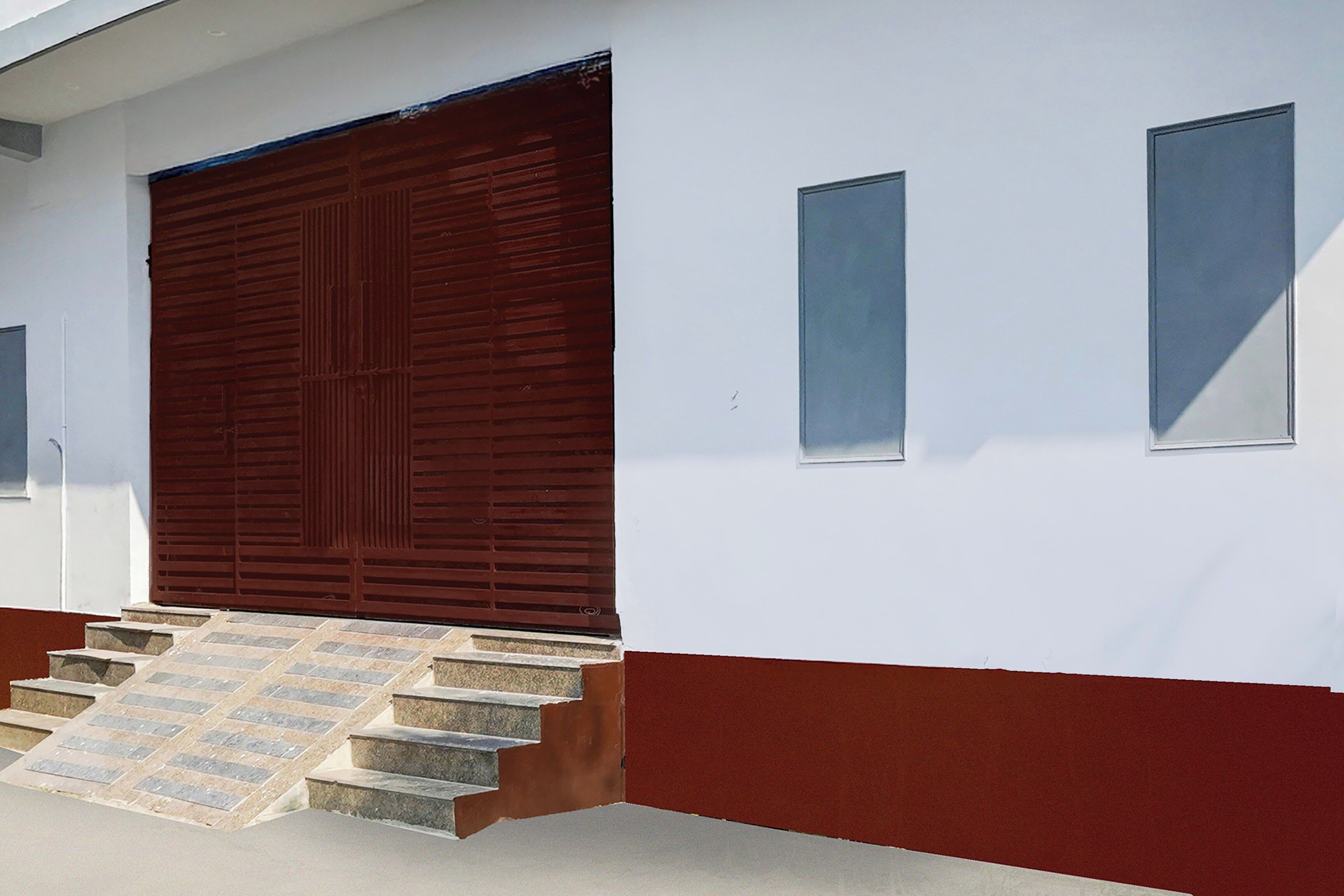 Un edificio con puerta roja, paredes blancas y una serie de escalones de piedra que conducen a la entrada.