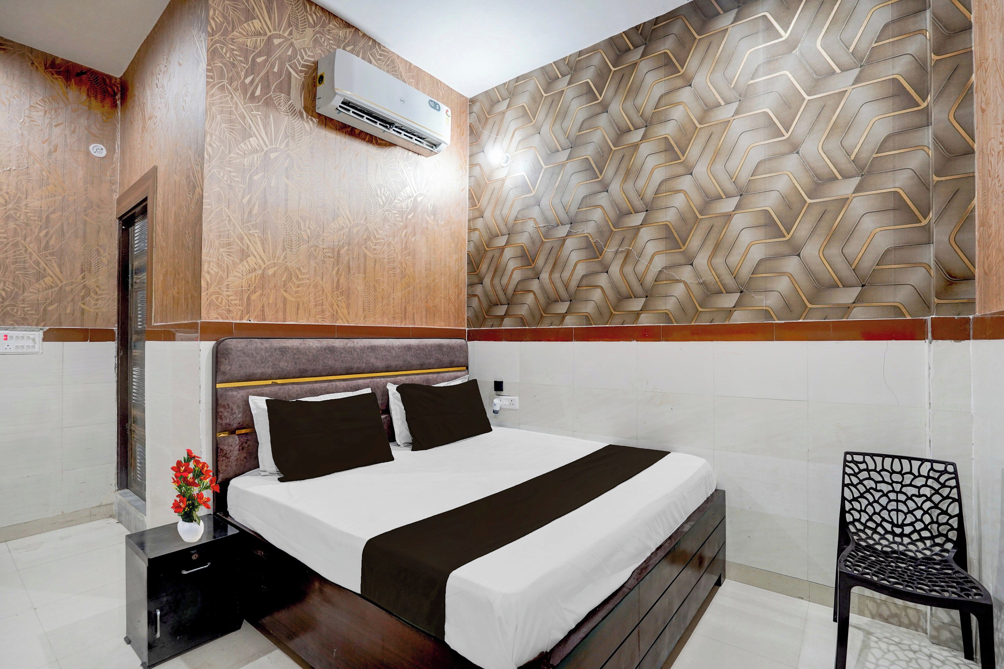 Quarto de hotel com cama, uma cadeira, mesa de cabeceira e ar condicionado.