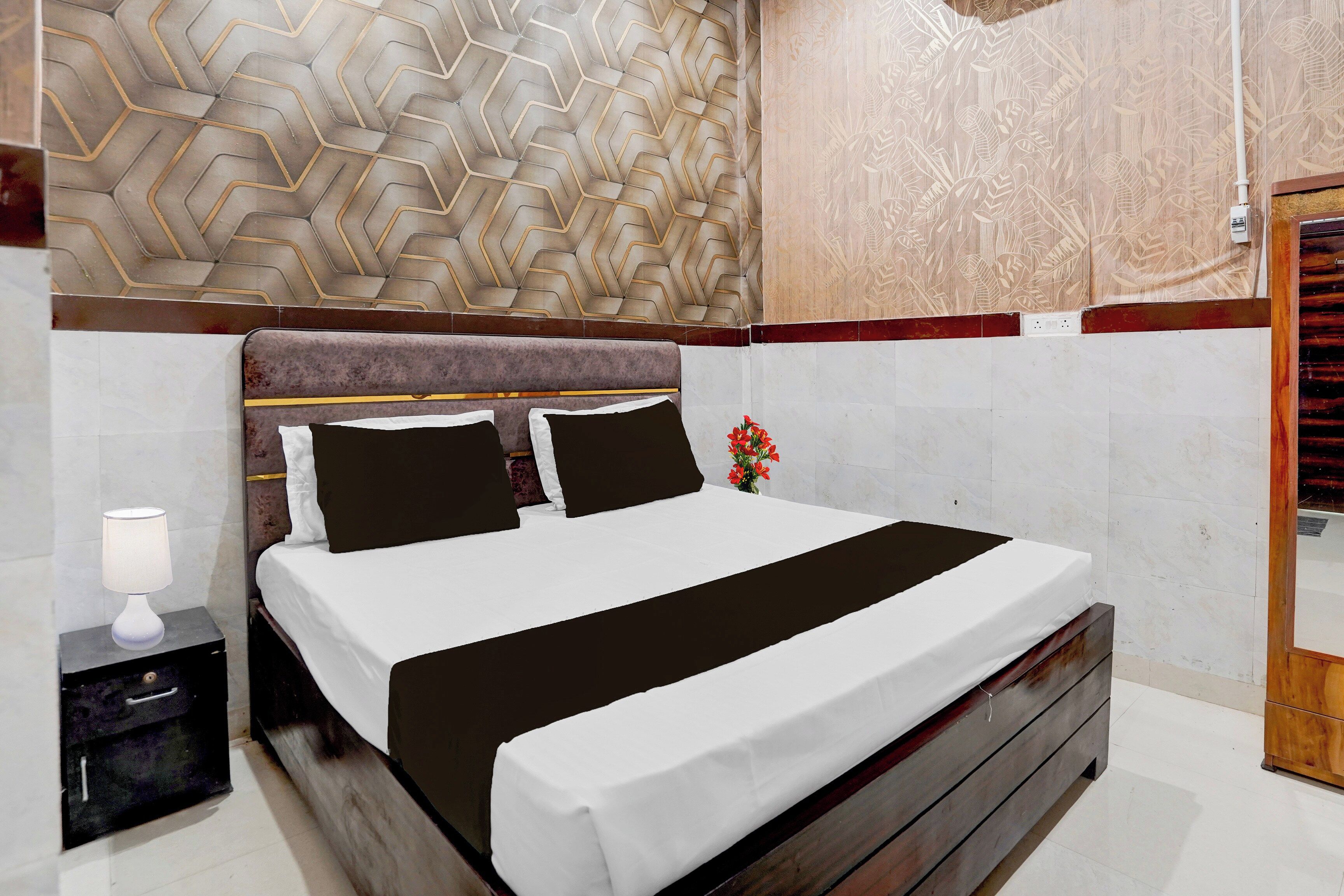 Quarto com cama, mesa de cabeceira e criado-mudo.