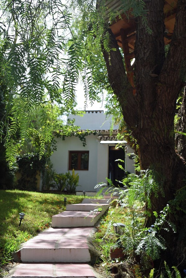 A pathway leading to a building with a white facade and a dark roof.