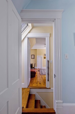 A hallway leading to a room with a wooden floor, a door, and a staircase. - Historic Ptown Charm - 3BR, Yard, AC, Parking (Provincetown)