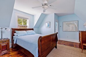 A bedroom with a wooden bed, a ceiling fan, a window, and a framed map on the wall. - Historic Ptown Charm - 3BR, Yard, AC, Parking (Provincetown)
