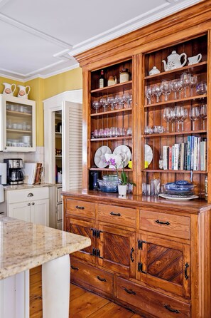 Una cocina con armarios de madera, encimera de mármol y diferentes utensilios de cocina.