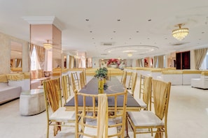 Un comedor espacioso con una larga mesa, numerosas sillas y un arreglo floral central.