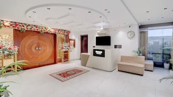 Un interior moderno con una puerta de madera, una recepción, un sofá y un televisor.