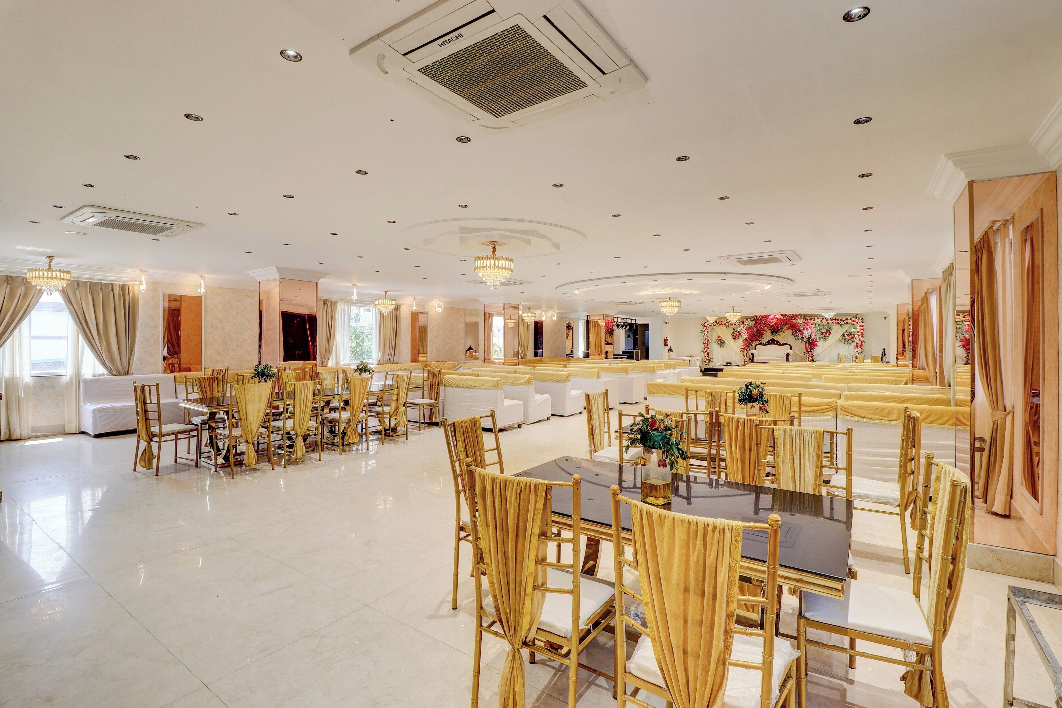 A spacious banquet hall with high ceilings, chandeliers, and rows of tables and chairs.