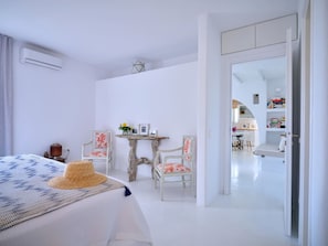A bedroom with a bed, a small table, two chairs, and a mirror. - Villa Kyma - Greek Summer (Kamares Naousas)