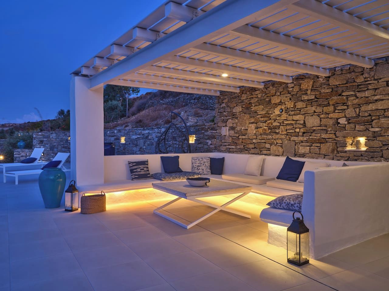 An outdoor seating area with a stone wall backdrop, a white sofa, and a coffee table.