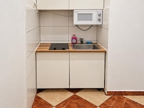 A compact kitchen with a microwave, sink, and wooden countertop. - A Month in Vienna 1BR Apartment (Wien)