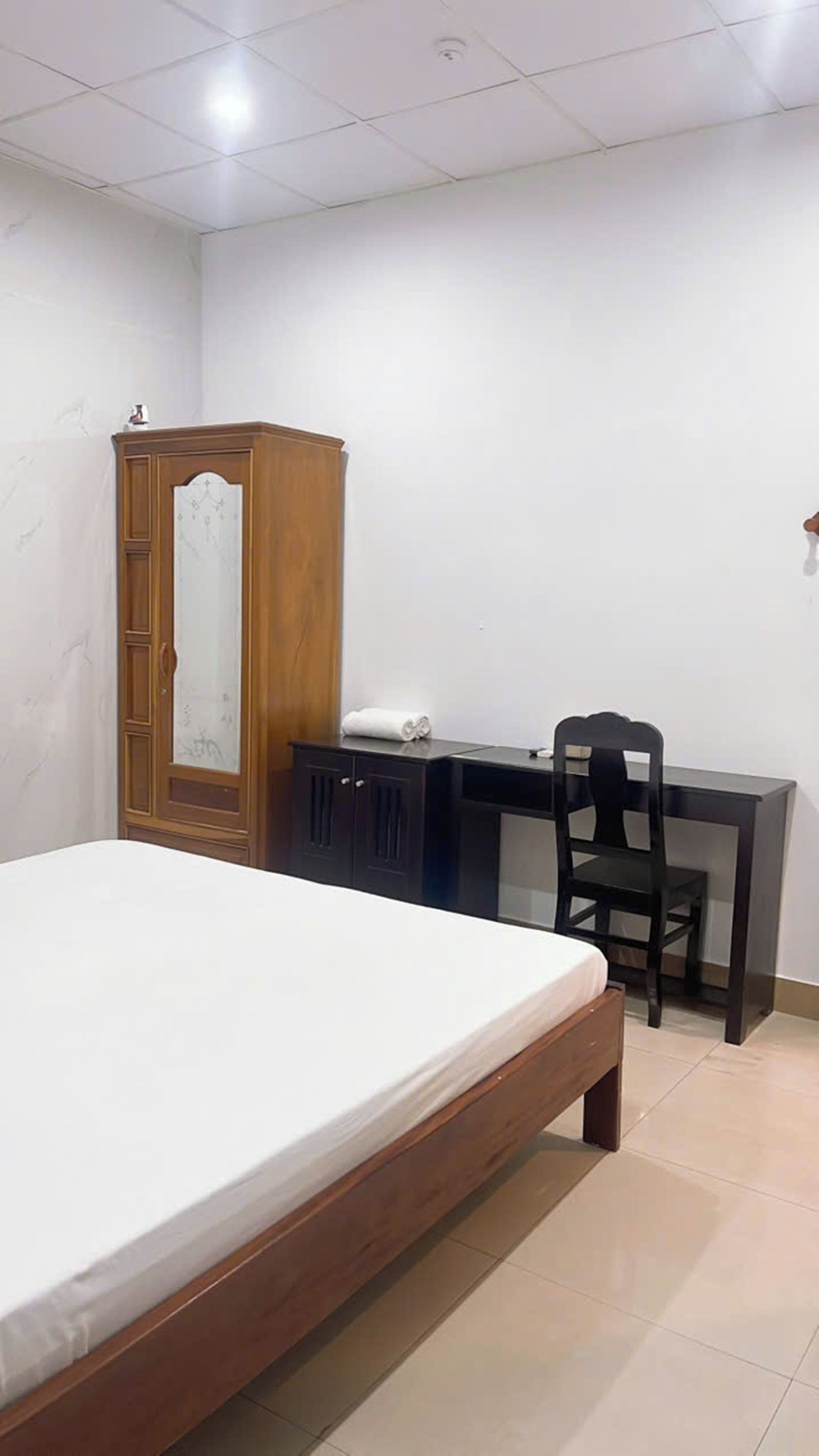 Une chambre à coucher avec un lit, un bureau, une chaise et une armoire.