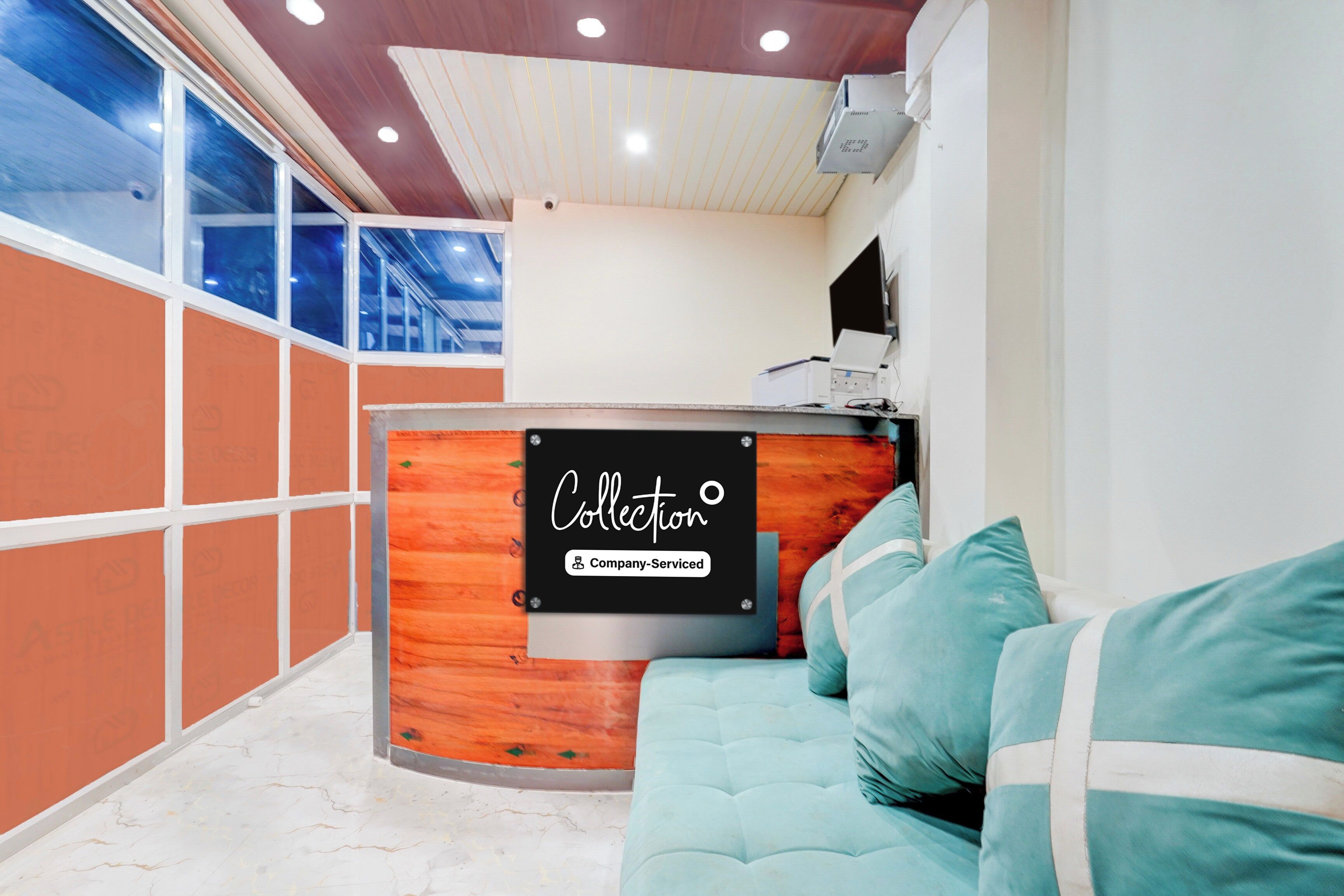 A reception area with a wooden reception desk, a sofa, and a large window.