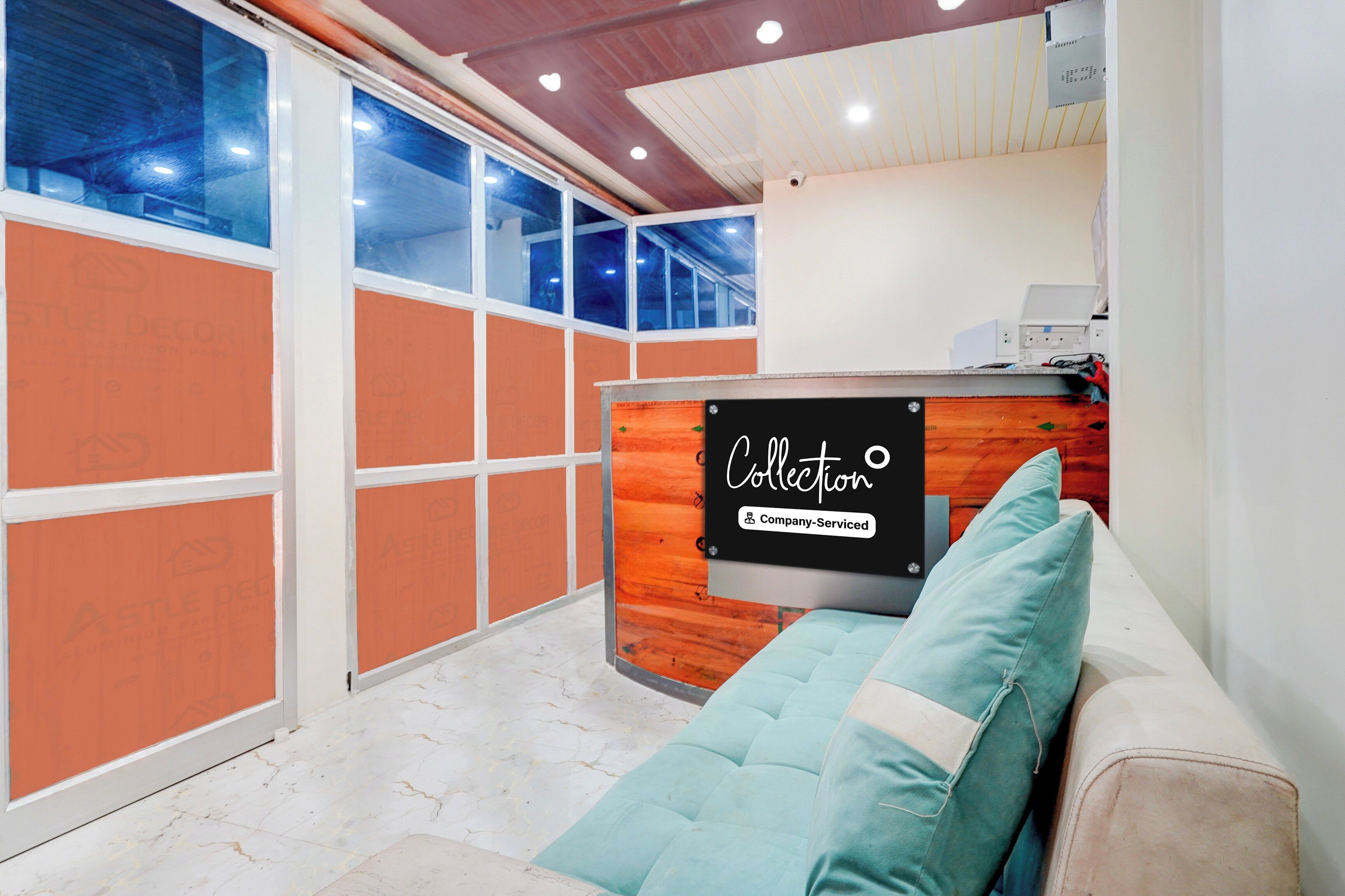 A modern interior with a sofa, a sign indicating 'Collection' and 'Company-Serviced', and a large window with a view.