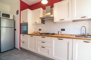 A kitchen with white cabinets, a stainless steel refrigerator, an oven, a gas stove, and a sink. - New Listing (Padova)