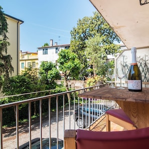 A balcony with a table, a bottle of wine, and a view of a residential street. - New Listing (Padova)