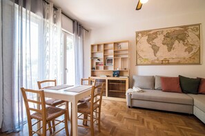 A room with a dining table, chairs, a sofa, a bookshelf, and a large world map on the wall. - New Listing (Padova)