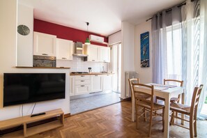 Een moderne keuken met witte kasten, een inbouwoven en een eethoek met een tafel en stoelen.