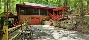 Une cabane à l’extérieur rouge, avec un escalier en pierre et un chemin de gravier menant à une terrasse en bois.