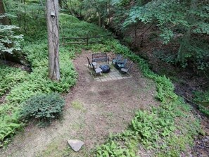 A forested area with a paved patio, a bench, and outdoor seating. - Apartment with a Peaceful Cabin Feel and Coosawattee River Resort Amenities (Ellijay)