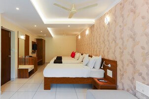 Habitación de hotel con cama doble, escritorio, armario, ventilador de techo y papel tapiz estampado.