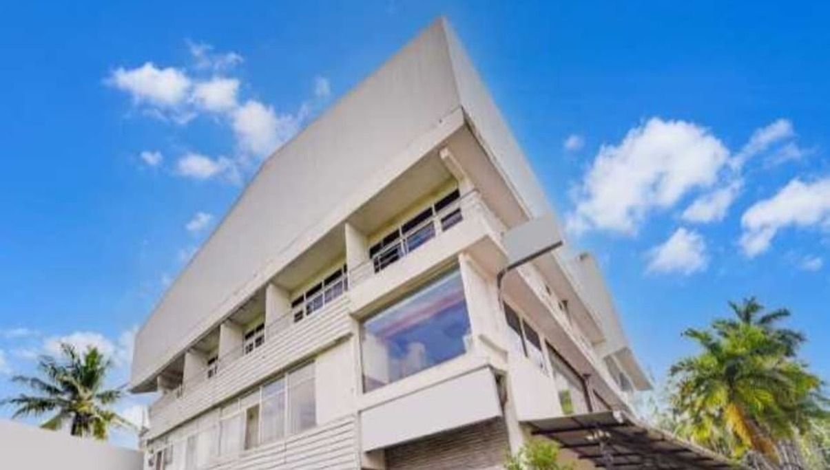 Um edifício de vários andares com telhado plano, janelas grandes e uma varanda.