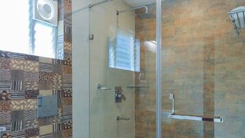 A modern bathroom with a glass shower enclosure, a toilet, and a patterned wall.