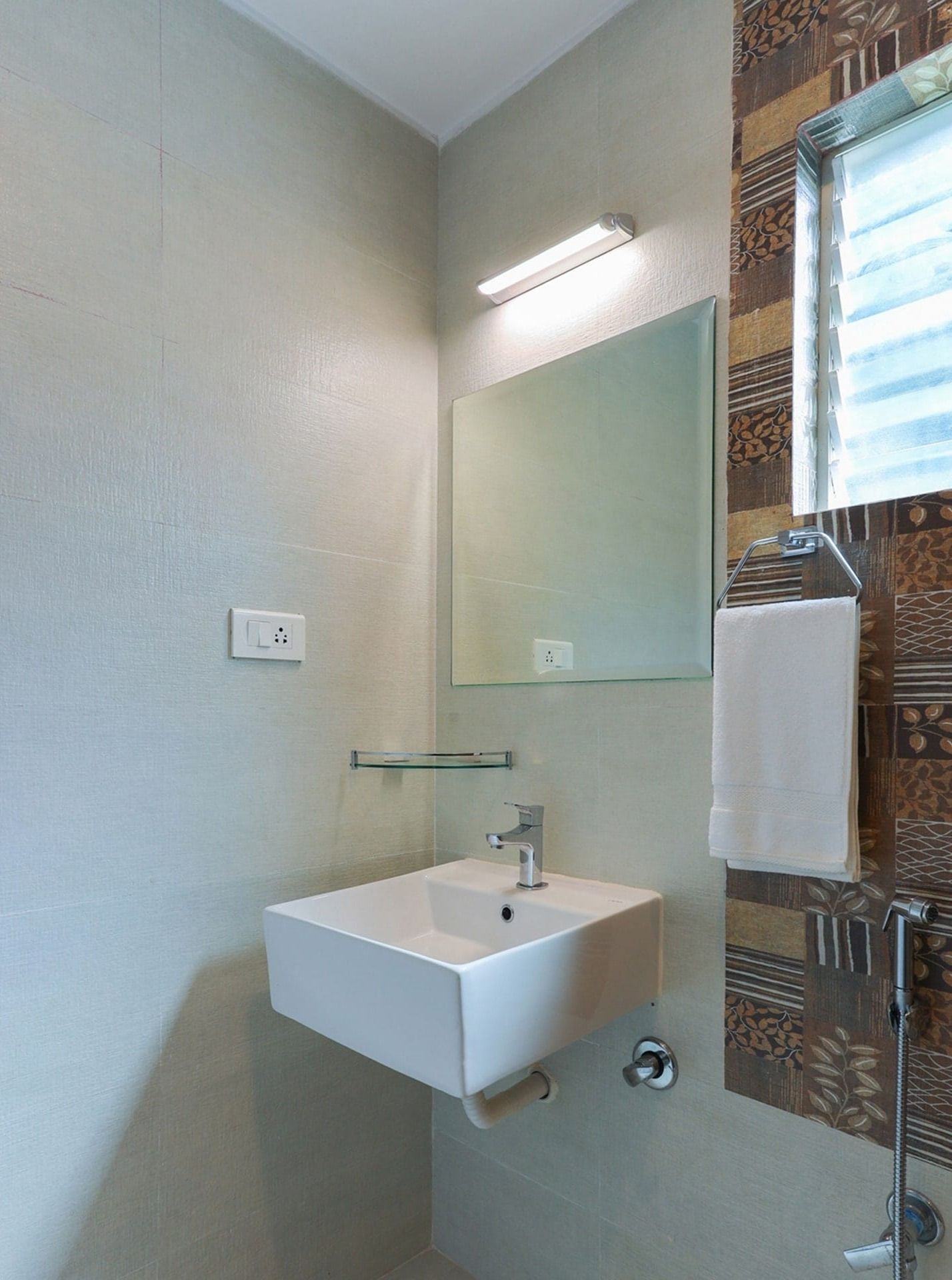 Un baño con un lavabo blanco, un espejo y un perchero para toallas.