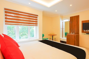 Une chambre d’hôtel avec un lit, une petite table, une chaise, un miroir et un téléviseur.