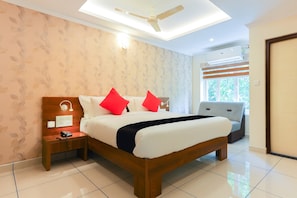 Une chambre d’hôtel avec un lit, une table de chevet, une lampe et un ventilateur de plafond.