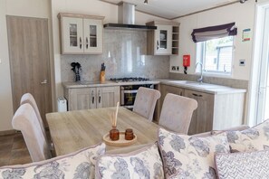 A compact kitchen with a dining area, featuring a stove, oven, and cabinets. - Lodge Sleeps 8 - Hot Tub - Dog Welcome (Lincoln)