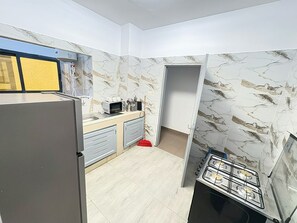 A compact kitchen with a refrigerator, microwave, and gas stove. - New Listing (Abidjan)
