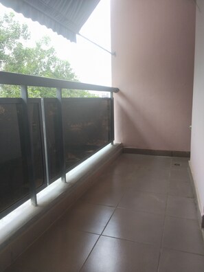 A balcony with a metal railing, a tiled floor, and a pink wall. - New Listing (Abidjan)