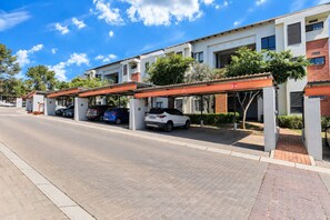 A modern building with a covered parking area and multiple cars parked. - Tee Off & Unwind at Jackal Creek by ctha (Roodepoort)