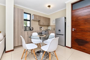Cocina compacta con mesa, sillas y refrigerador.