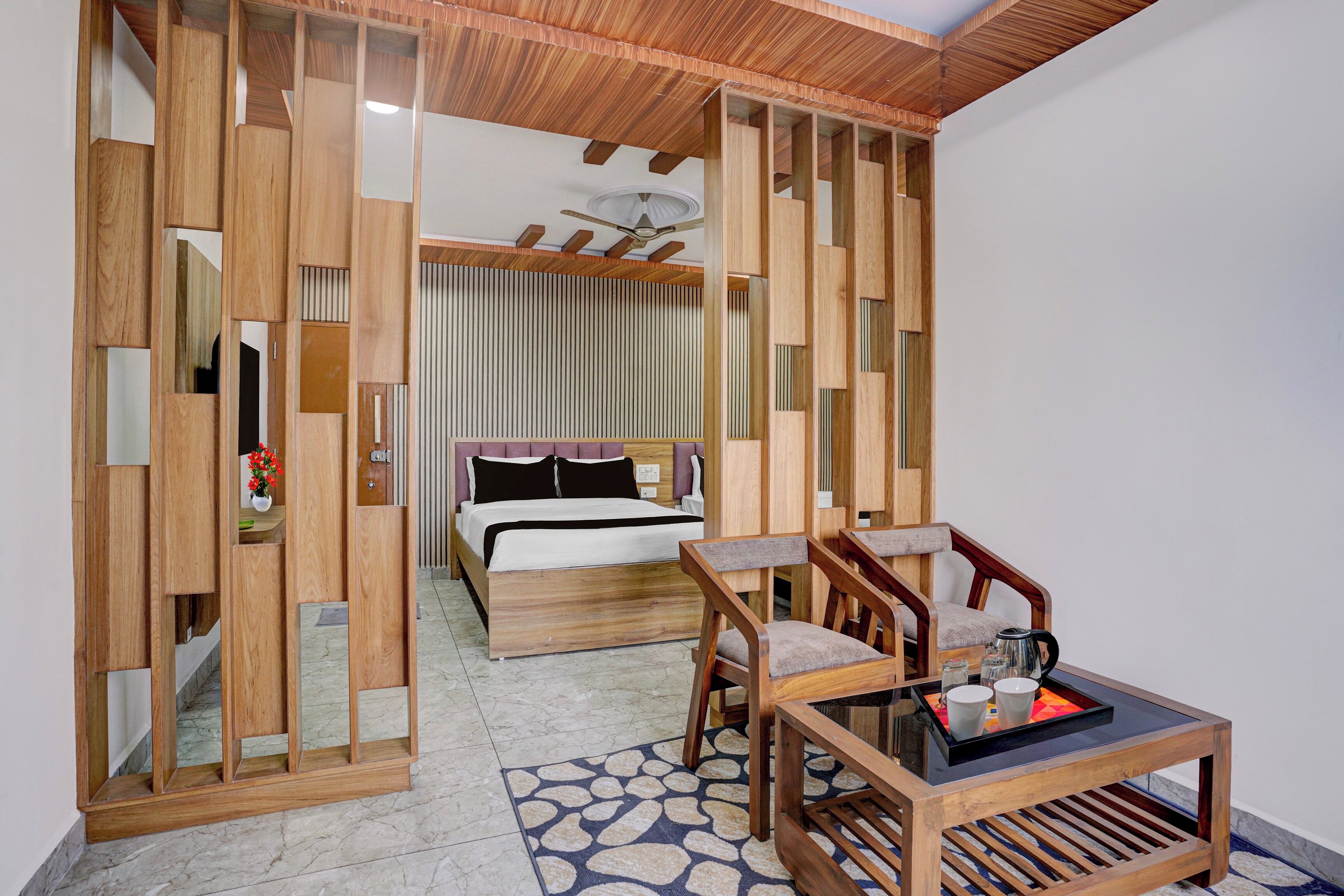 A room with a bed, a wooden partition, a chair, a table, and a patterned rug.