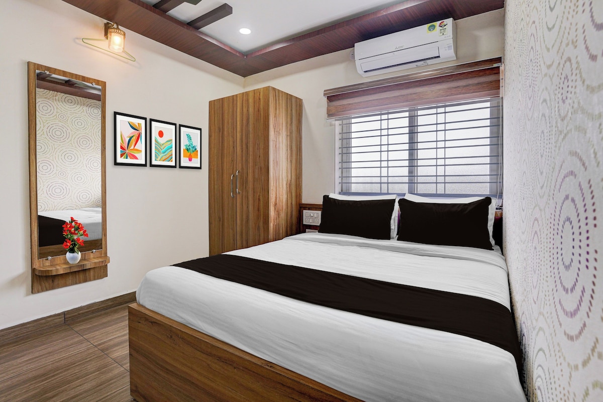 A bedroom with a bed, a wardrobe, a mirror, and framed artwork on the wall.