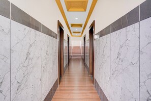 A corridor with marble walls and wooden flooring, leading to an elevator area. - Townhouse KMF Dharwad (Dharwad)