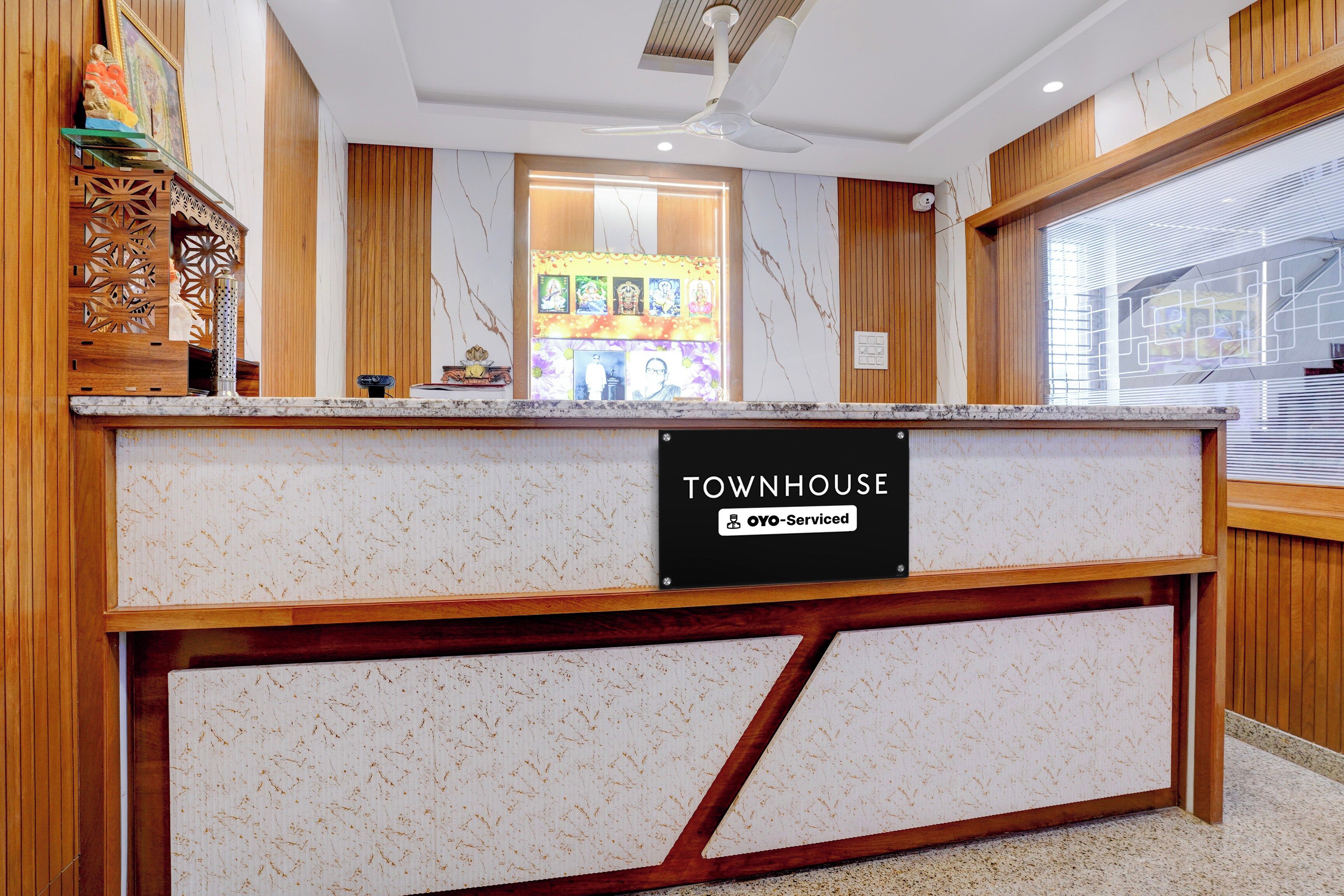 A reception desk with a marble top, a sign reading 'TOWNHOUSE' and 'OYO-Serviced', and a ceiling fan above.