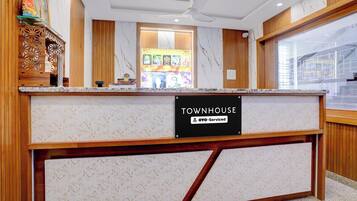 A reception desk with a marble top, a sign reading 'TOWNHOUSE' and 'OYO-Serviced', and a ceiling fan above.
