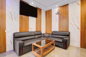 Una sala de estar moderna con un sofá modular, una mesa de centro de madera y un televisor de pantalla plana montado en la pared.
