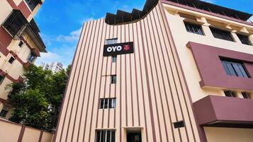 Un edificio de hotel con fachada a rayas verticales, un cartel que indica que es un Hotel OYO y un cielo despejado al fondo.