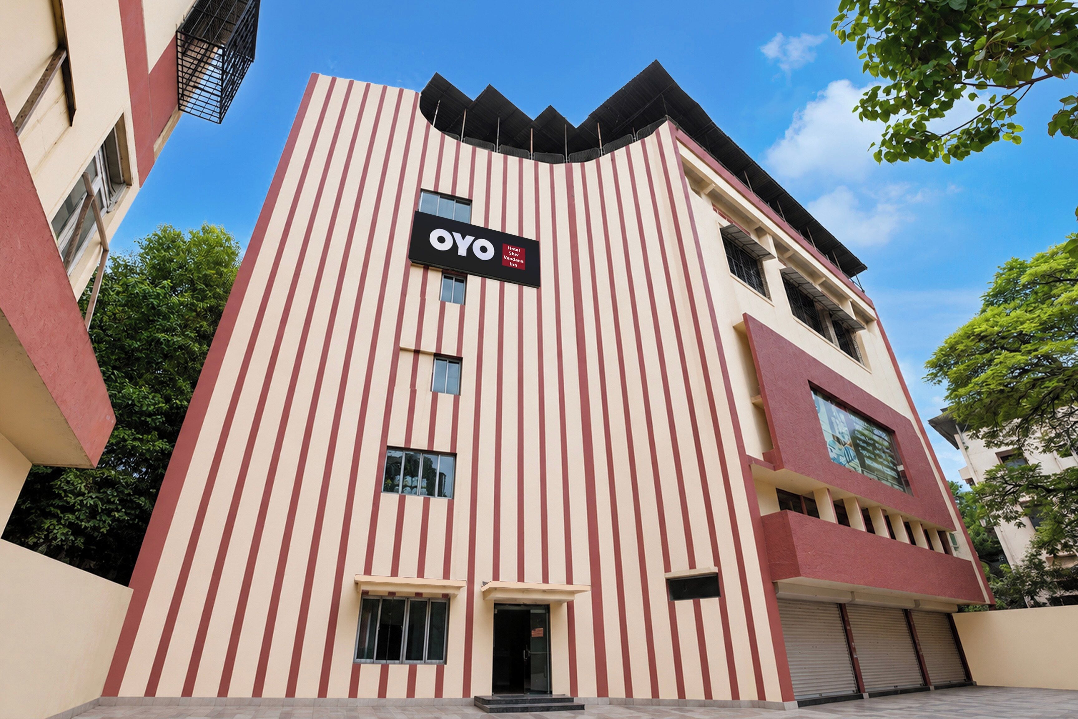 Un edificio de hotel con fachada a rayas verticales, un letrero llamativo y un techo plano.