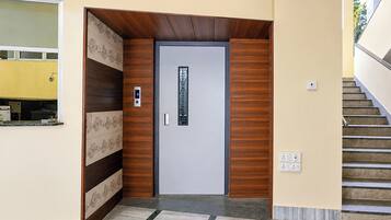 Una entrada moderna con diseño de paneles de madera, una puerta con panel de vidrio y una escalera a la derecha.