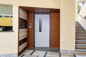Una entrada moderna con diseño de paneles de madera, una puerta con panel de vidrio y una escalera a la derecha.