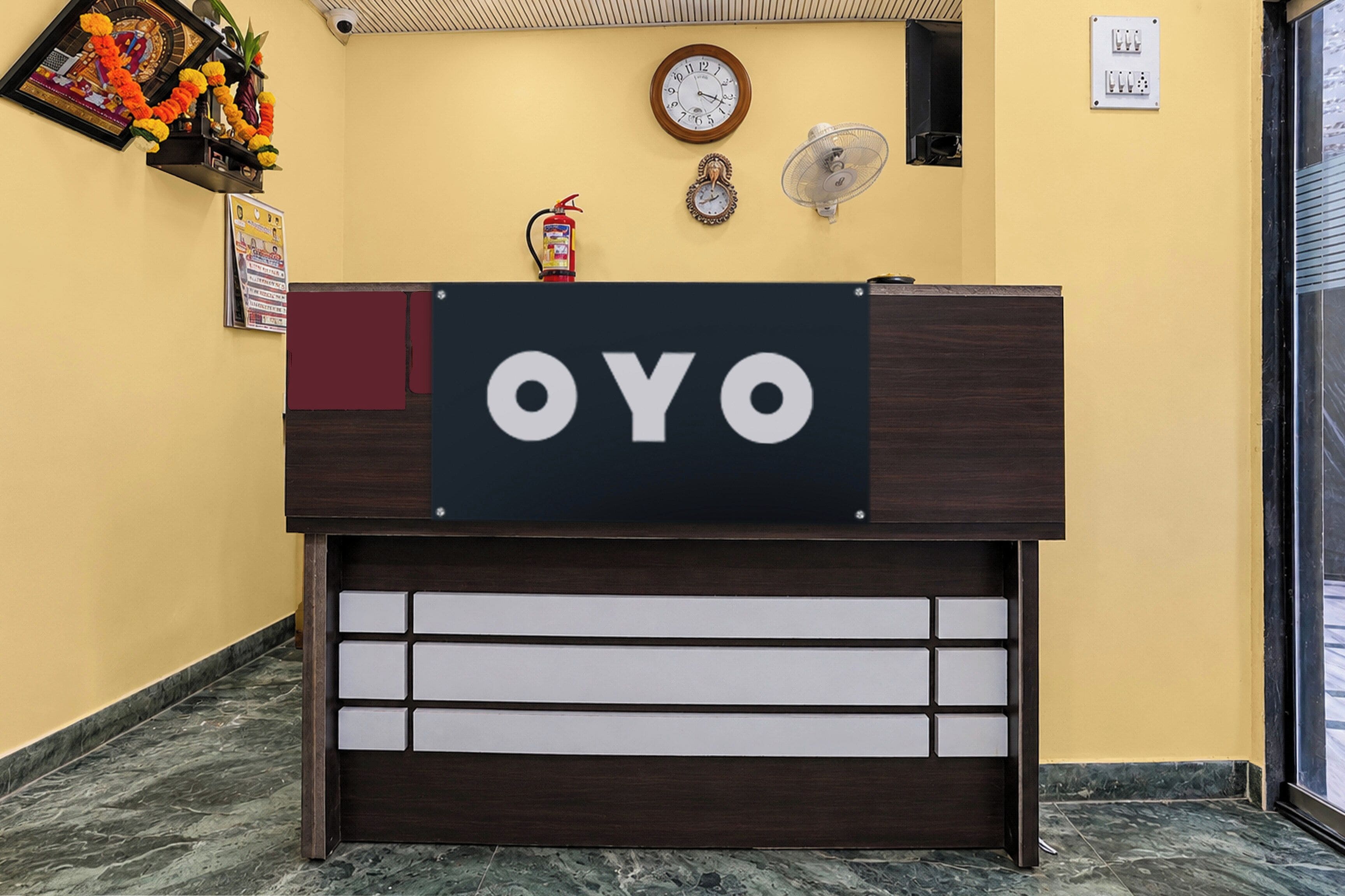 Un comptoir d'accueil avec une enseigne indiquant « OYO » et un extincteur fixé au-dessus.