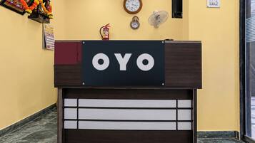 A reception desk with a sign that reads 'OYO' and a fire extinguisher mounted above it.