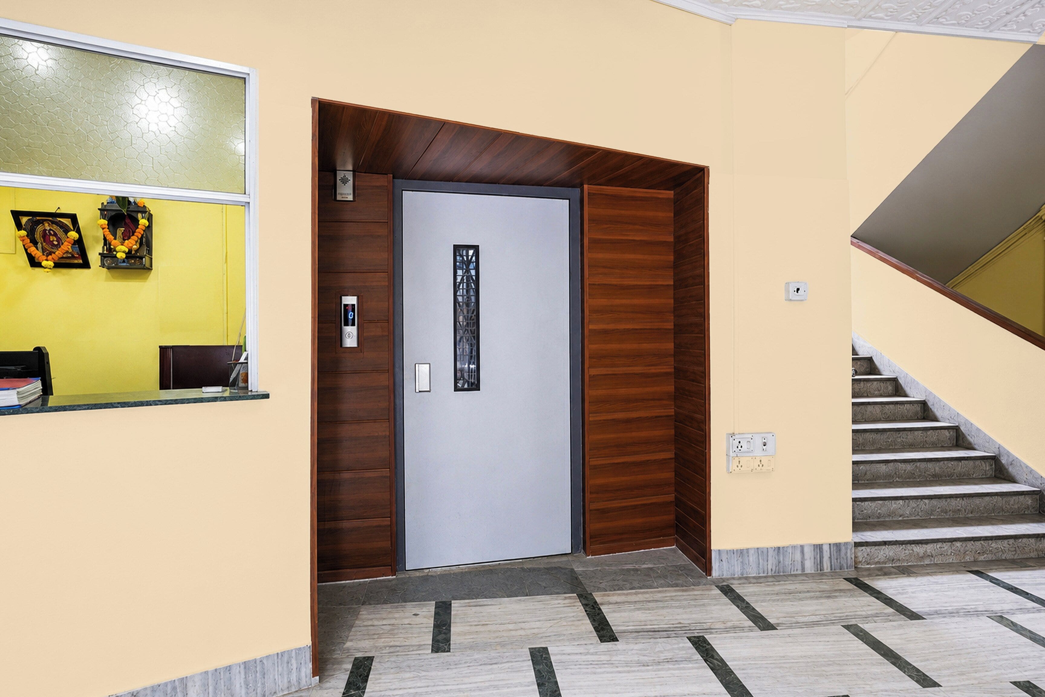 Zona de recepción con mostrador, puerta y escalera.